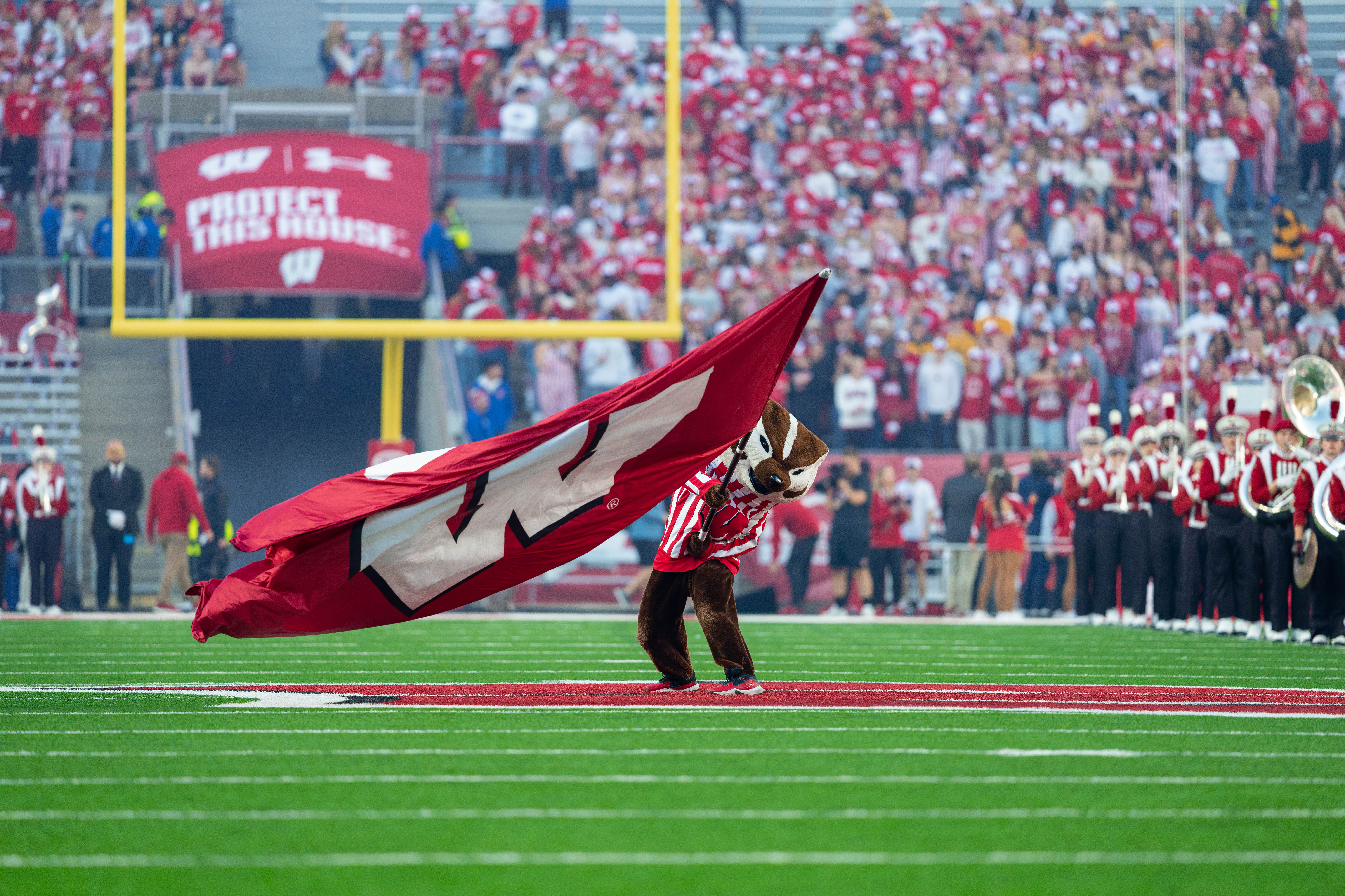 Oct 11, 2025; Madison, Wisconsin, USA; Bucky Badger waves a big Wisconsin flag at mid field before the Wisconsin Badgers plays the Iowa Hawkeyes at Camp Randall Stadium. Mandatory Credit Photography by Ross Harried for Second Crop Sports.