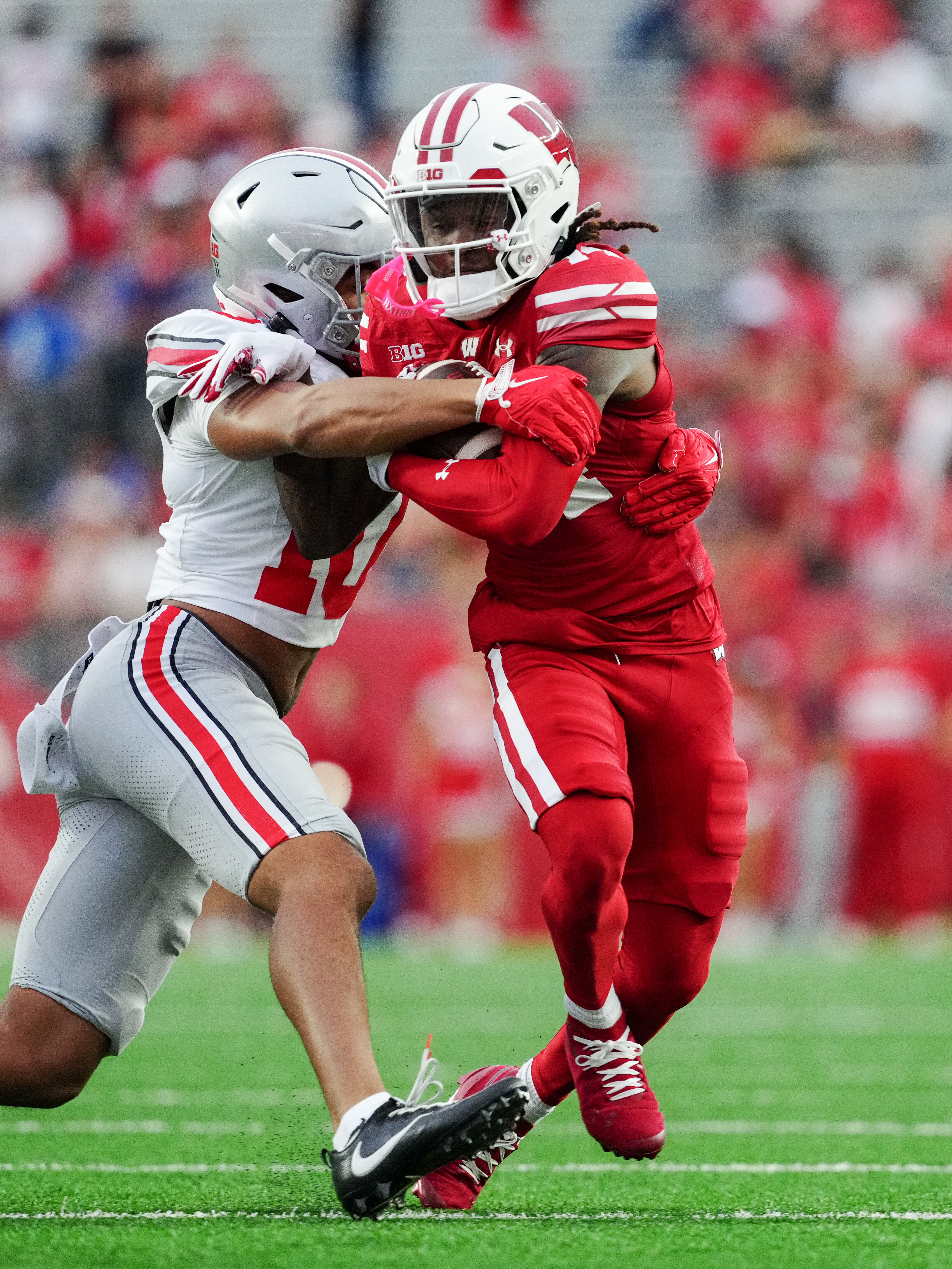 Oct 18, 2025; Madison, Wisconsin, USA; Wisconsin Badgers wide receiver Dekel Crowdus (14) is tackled by Ohio State Buckeyes safety Faheem Delane (10) in the second half at Camp Randall Stadium on October 18, 2025 in Madison, Wisconsin. Photography by Ross Harried for Second Crop Sports.